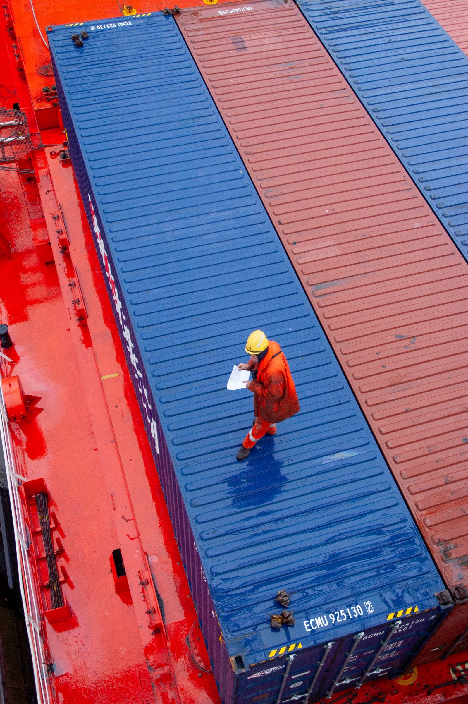Port worker checking documents beside shipping containers